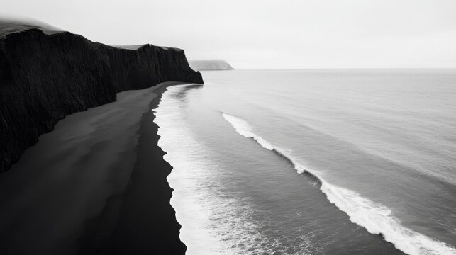A black and white image of rolling ocean waves crashing onto a deserted shore, dramatic and moody