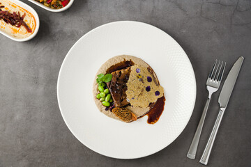 Gourmet plate of slow-cooked meat, morel mushrooms, puree and tuile