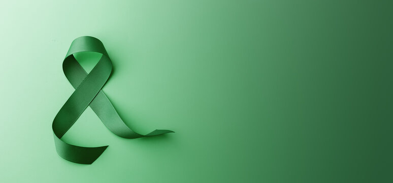 Mental Health Awareness Concept. Self Care, Positive Thinking, Happy and Optimistic Mind. a Green Ribbon lay on Green background. Table top view