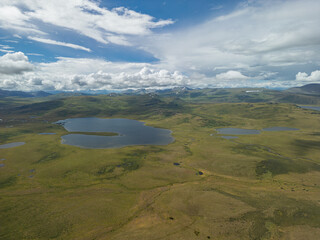 Fototapeta premium Aerial view of a green valley surrounded by mountains, where there are many lakes. Lakes in the Altai valley, view from a quadcopter.