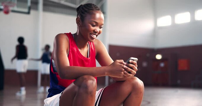 Basketball, phone and woman at court for sports break, check score and wellness app. Smile, exercise and African person on mobile for online text, scroll message and reading training tips for fitness