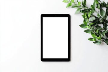 Modern tablet with fresh greenery on a white surface