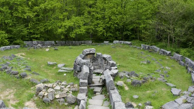 Approaching drone shot tilting above the ruins of the round-domed chamber of Mishkova Niva tomb in an ecological reserve located on Strandzha Mountain, in Bulgaria.
