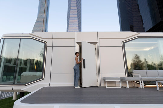 Woman entering a modern modular home with skyscrapers in the background