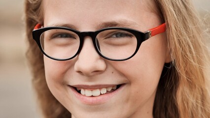Smiling blonde 10 year old girl dresses glasses. Face close-up.