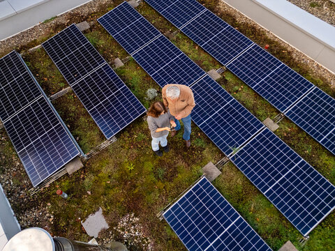 Grandfather and granddaughter bonding on a rooftop with solar panels