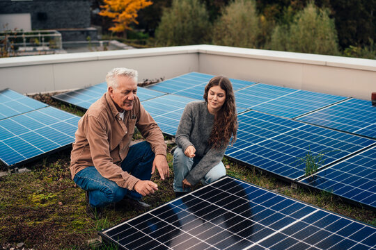 Grandfather and granddaughter discussing solar panels on a rooftop
