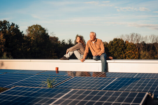 Grandfather and granddaughter enjoying time together on a rooftop with solar panels