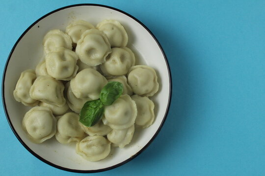 Vegetarian dumplings with basil greens on a blue fne with space for copyspace text. Vegetarian food