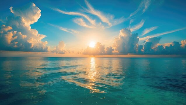 Rising sun at the horizon over a serene ocean or sea. On the azure sky, fluffy white clouds.