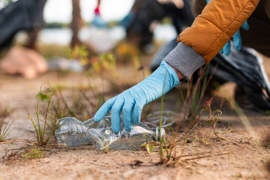 Volunteer picking up plastic bottle during cleanup event in nature