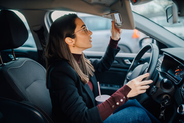 Businesswoman adjusting sun visor mirror while driving car