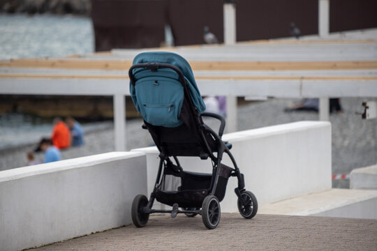 A blue stroller is sitting on a cement wall