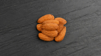 Almonds pile, nut group, whole almond seeds, brown scattered fruit kernels, dry raw nuts on black