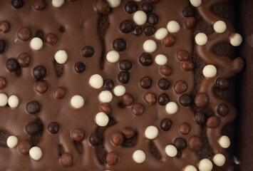 Chocolate brownie cake texture background sprinkled with white and dark balls, brounie banner