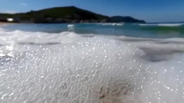 4K close-up and wide shots of foamy ocean waves washing ashore, capturing fluid dynamics, bubbles, and the soothing sound of waves gently lapping a peaceful sandy beach

