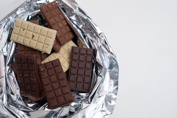 Multicolored chocolate bars placed on a light background. Healthy eating concept, delicious chocolate candies, diet, sugar
