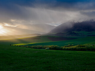 Mountain landscape. A view of the green hills with storm clouds looming over them. You can see the approaching rain from the clouds