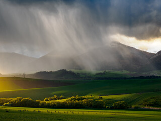 Mountain landscape. A view of the green hills with storm clouds looming over them. You can see the approaching rain from the clouds