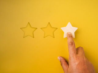 1 star rating reviews button pressed by hand on yellow background. Poor customer satisfaction, low evaluation, negative feedback, specific service or experience survey, business marketing concepts.