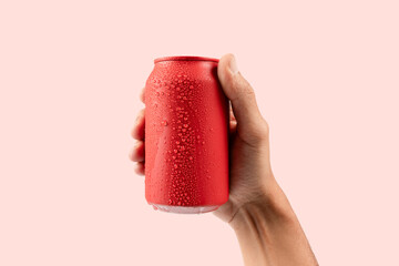 Male hand holding a red aluminium drinking soda can mockup isolated on pink background
