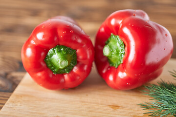 Red bell pepper on a cutting board with dill and parsley