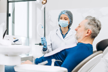 Obraz premium Professional stomatologist standing near her patient and demonstrating her work