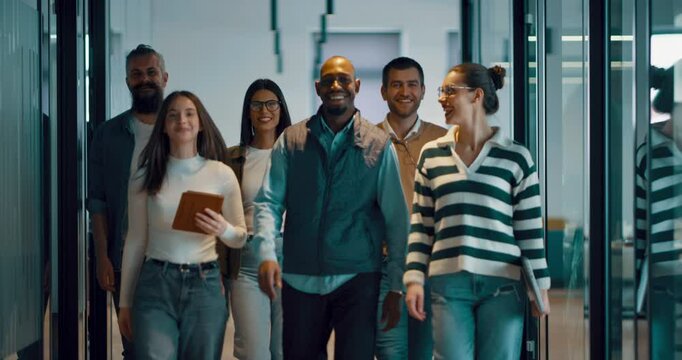 Business team in a modern open space startup office walking together. Diverse group of businesspeople smiling while having a discussion. Successful mixed race colleagues collaborating on a new project