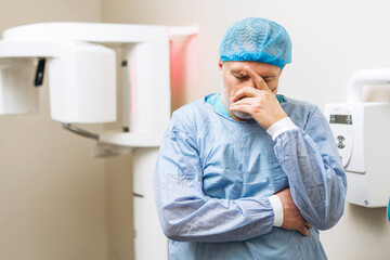 Portrait of sad male dentist in uniform standing in X-Ray room in clinic