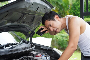 man checking engine with smartphone light