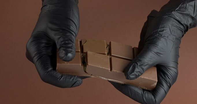 Hands in gloves break, cracking Dubai chocolate with pistachio paste and kataifi. Slow motion.