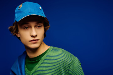 Young man showcases modern style in vibrant blue background exuding confidence and trendiness