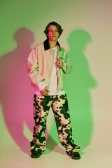 Trendy young man showcasing modern fashion style with vibrant neon lighting