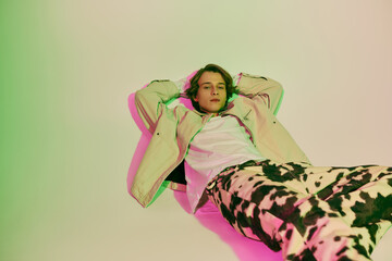 Young man showcases modern fashion trends with relaxed style in vibrant studio setting