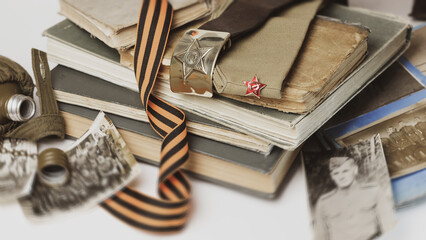Belt with buckle of a soldier of the Soviet Union, uniform cap with a red star and St. George's ribbon on a white background with old war photographs.