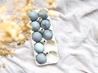 elegant easter composition with painted eggs, golden leaves and dried flowers on light linen background. easter background