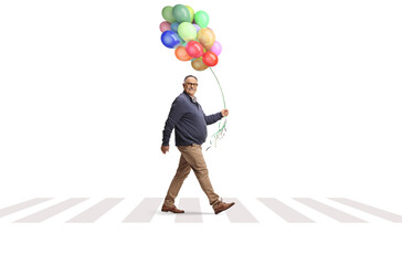 Mature man crossing a street with a bunch of colorful balloons
