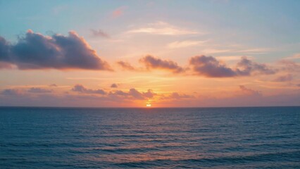 Obraz premium Glowing sunset over calm ocean with scattered clouds.