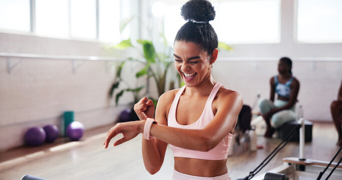 Fist pump, pilates and time with woman in studio, tracking performance progress of exercise routine. Fitness, training and watch with happy athlete person in gym class for goals, success or target