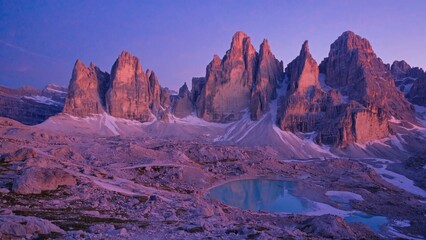 The iconic Cinque Torri peak and the majestic surrounding landscape of the Dolomites mountains under a vibrant sunset sky.