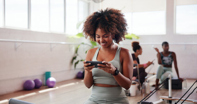 Happy, woman and phone in pilates class for exercise break, watching online video or streaming service. Fitness, yogi and girl with smartphone at gym studio for yoga tutorial, wellness tips or health