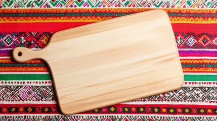 Flat lay of wooden cutting board on colorful traditional mexican fabric. Blank copy space on tabletop. Kitchen cooking background. Culinary template for menu design. Eatery serving mockup.