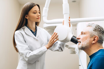 Female dentist with x-ray machine scanning male teeth at dental medical center