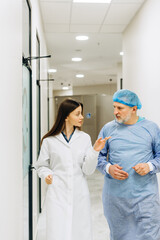 Obraz premium Two doctor colleagues walking in hall and discussing in medical clinic