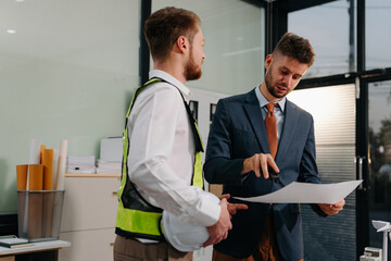 Obraz premium architect caucasian man working with colleagues mixed race in the construction site. engineer architect wearing safety helmet meeting.