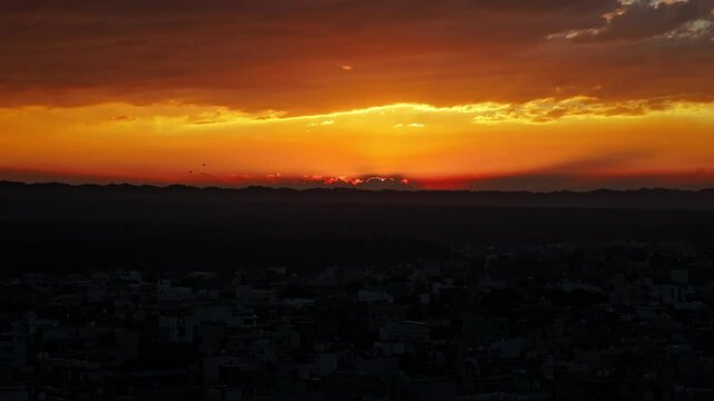 An aerial view of the picturesque city of Dehradun in Uttarakhand, India, captured during a breathtaking sunset. The cinematic shot showcases the city's blend of urban charm and natural beauty.