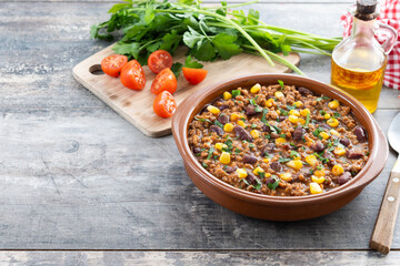 Traditional Mexican Chili con carne. Minced meat and vegetables stew in tomato sauce on wooden table
