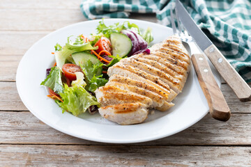 Healthy grilled chicken with salad on wooden table
