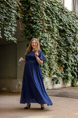 Woman in a long blue dress in the garden.