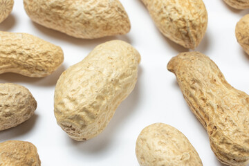 Macro whole unpeeled peanuts on a white background.